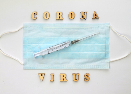 Scritta coronavirus con siringa e mascherina