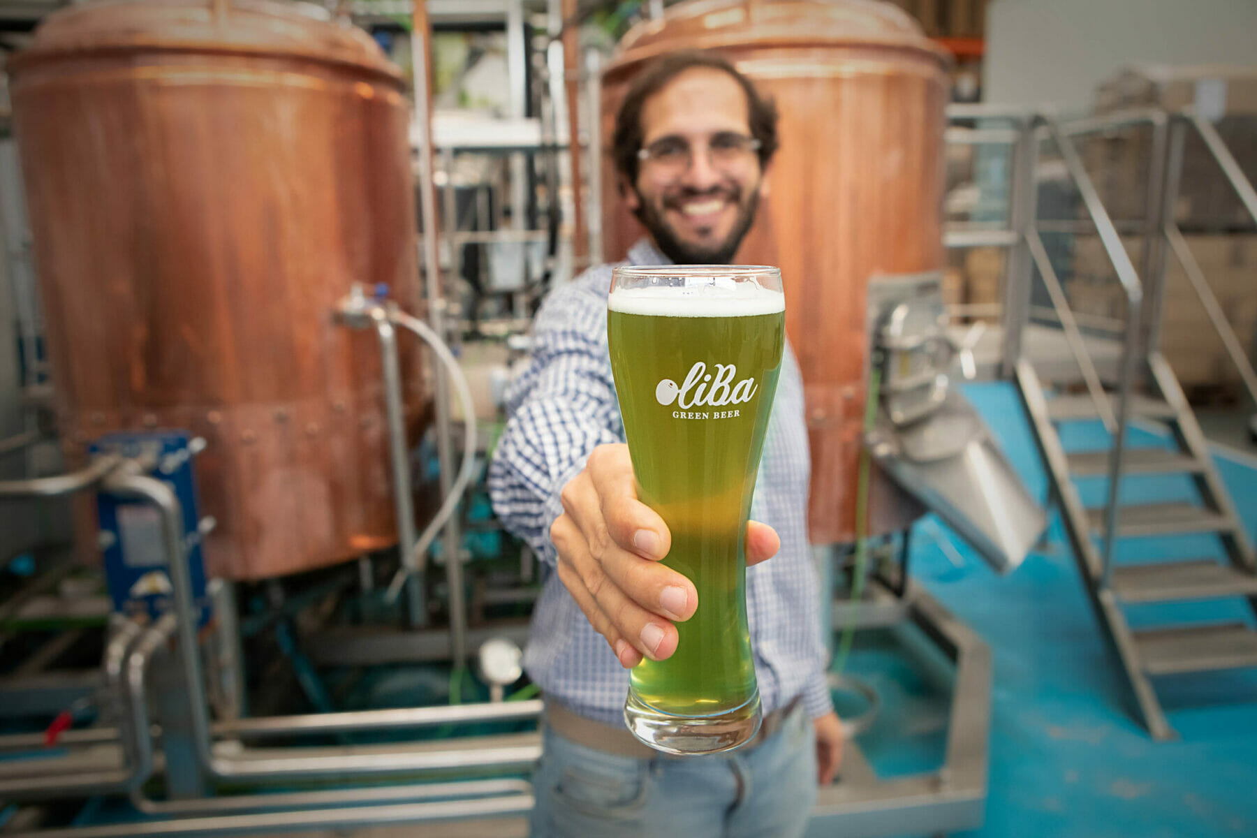 persona con in mano la birra OliBa Green e botti