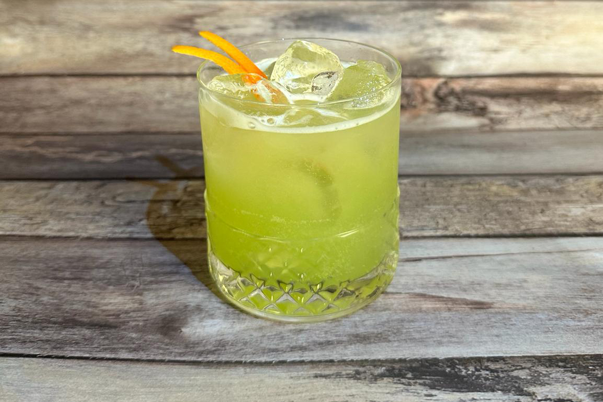 Un mocktail tropicale servito in un bicchiere basso, con ghiaccio e due zest di arancia