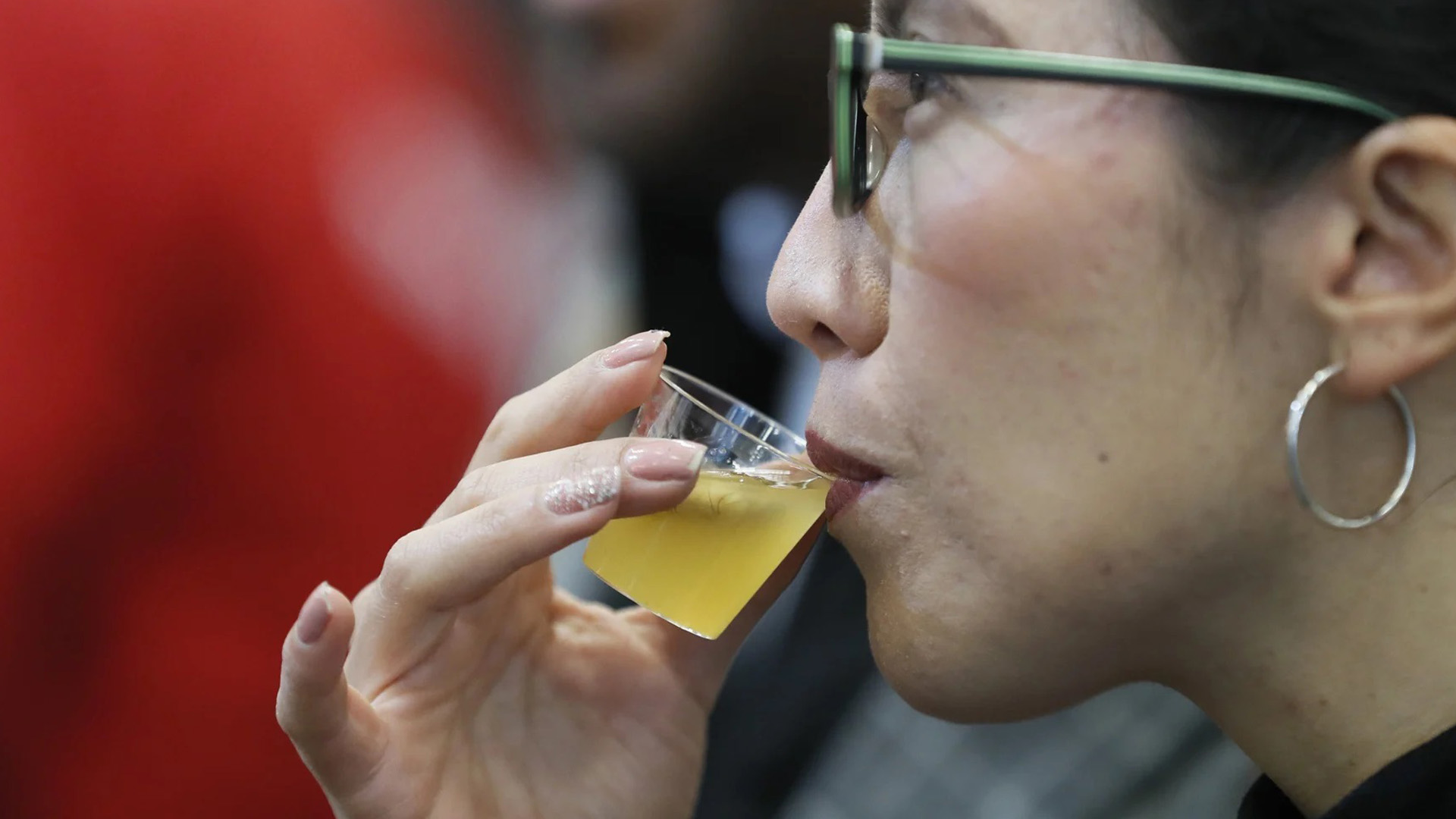 Una donna con occhiali e orecchini a cerchio sorseggia un bicchierino di Miske, il distillato nazionale dell’Ecuador, durante una degustazione