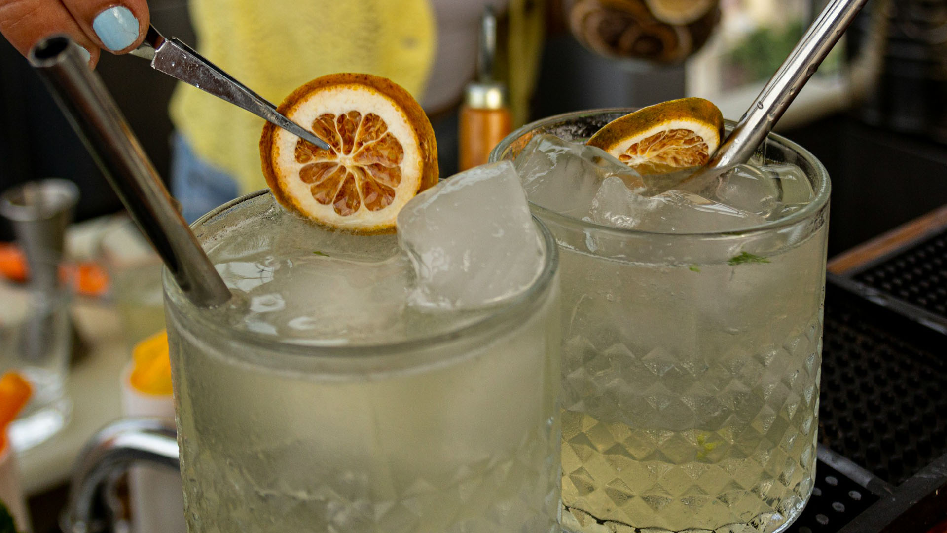 Due bicchieri di cocktail cubani serviti con ghiaccio e guarniti con fette di agrumi essiccati, pronti per essere degustati in un bar tropicale. Un esempio di bevande tradizionali di Cuba