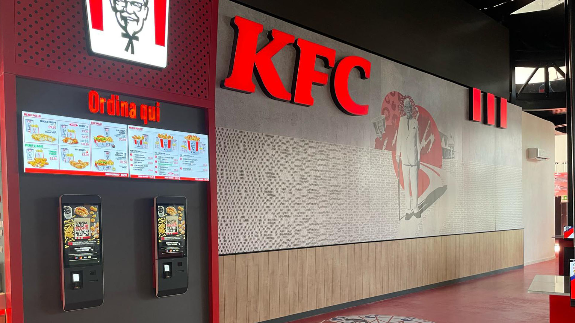 Interno del nuovo ristorante KFC a Segrate con moderni chioschi digitali per l’ordinazione, design contemporaneo e dettagli iconici del brand.