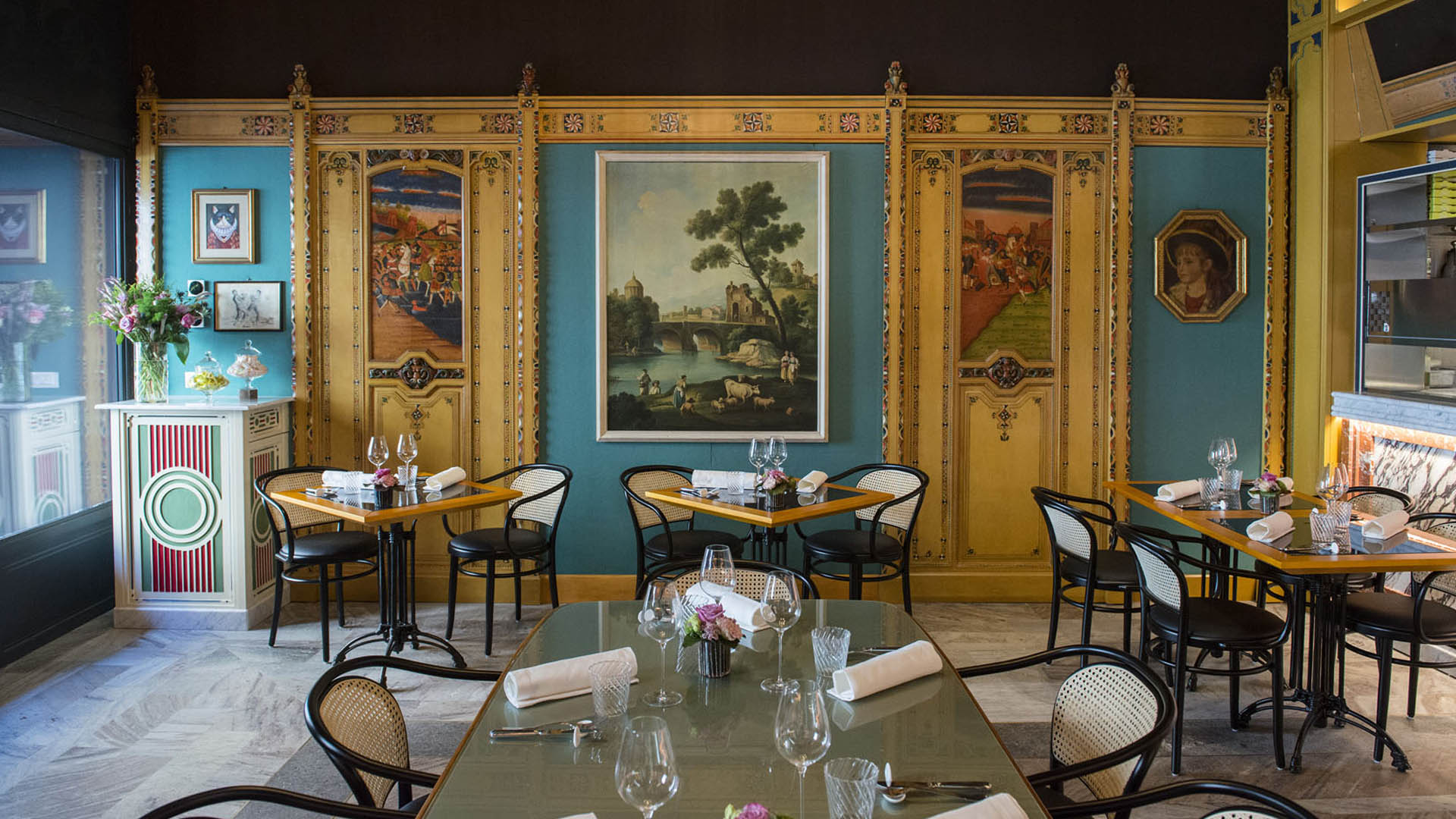 Sala interna elegante di VICO Pizza&Wine a Roma, con tavoli apparecchiati, arredi liberty e opere d’arte alle pareti, dove gustare la pizza al baccalà.