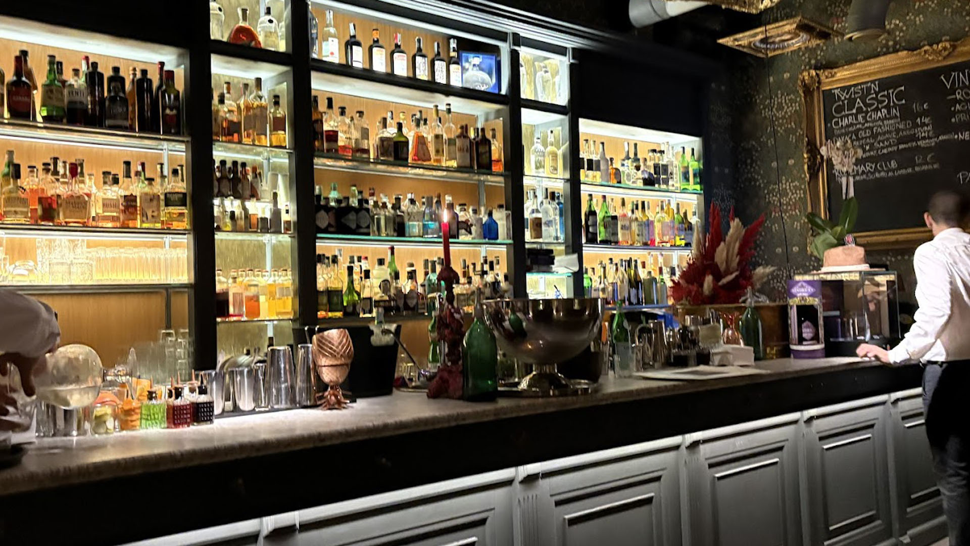 Interno sofisticato dell’Archivio Storico Cocktail Bar di Napoli, con bottigliera retroilluminata, bancone in marmo, cocktail tools e arredi eleganti in stile classico.