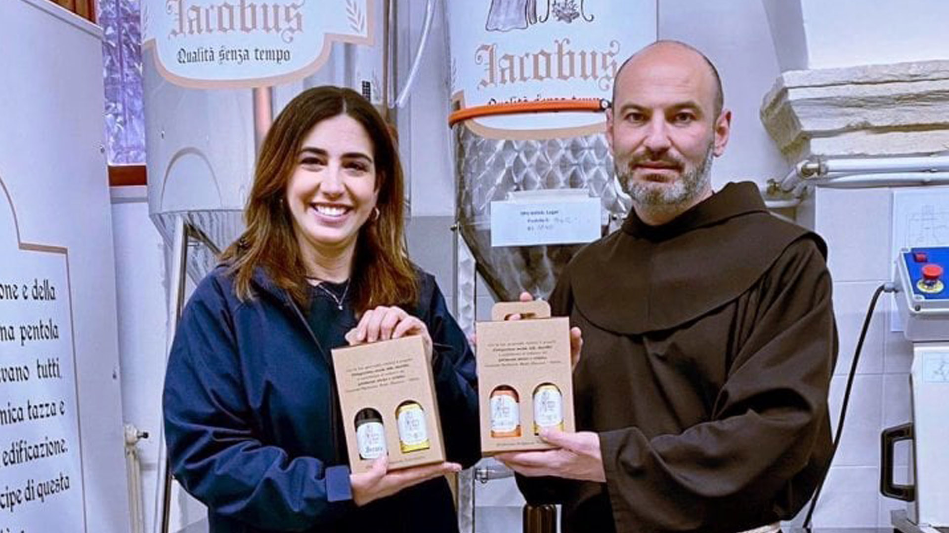 Due persone mostrano con orgoglio confezioni di birra artigianale Iacobus, prodotta nel convento di Bitetto in Puglia, simbolo di inclusione e solidarietà.