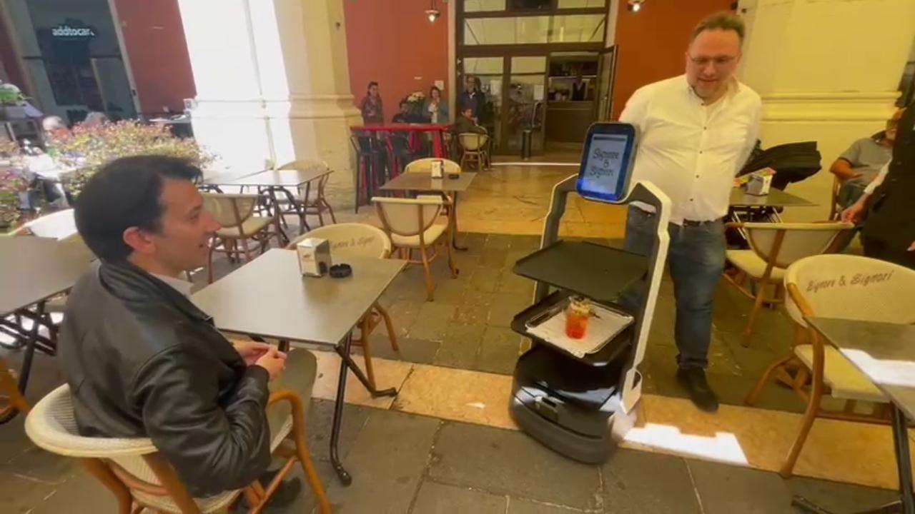 Cameriere robot in difficoltà tra i tavoli esterni di un bar