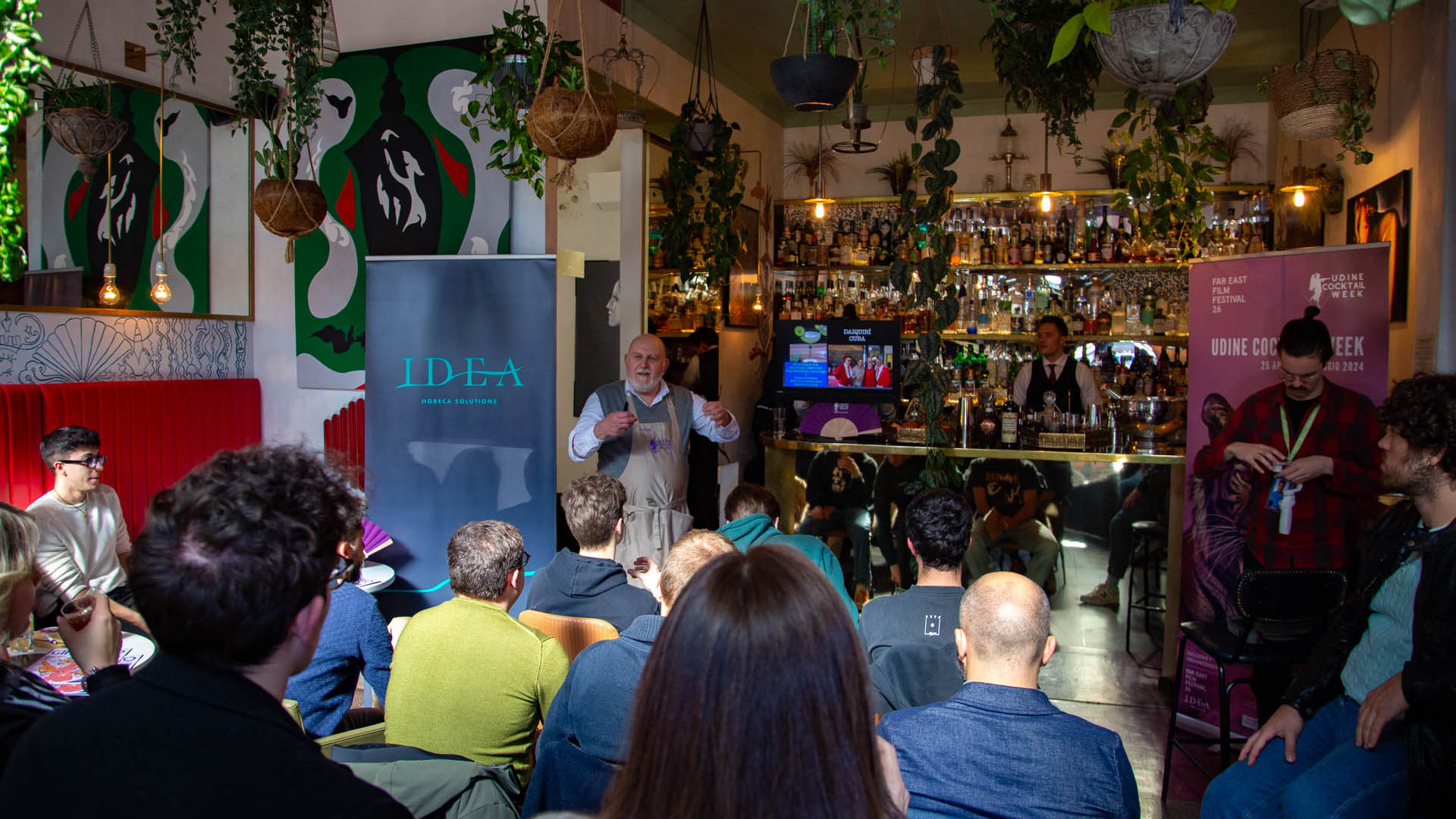 Presentazione alla Udine Cocktail Week 2025 con pubblico e relatori in un locale decorato, durante un evento dedicato alla mixology e al bere consapevole.