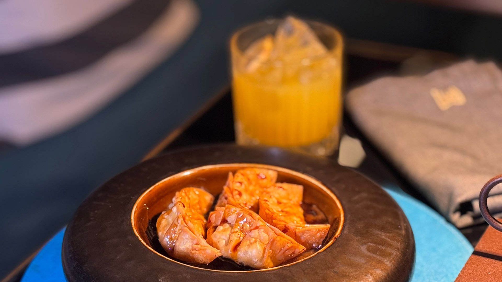 Gyoza di maiale serviti in ciotola scura con salsa e cocktail giallo in abbinamento, esempio di cocktail food pairing giapponese al Magnolia di Napoli.