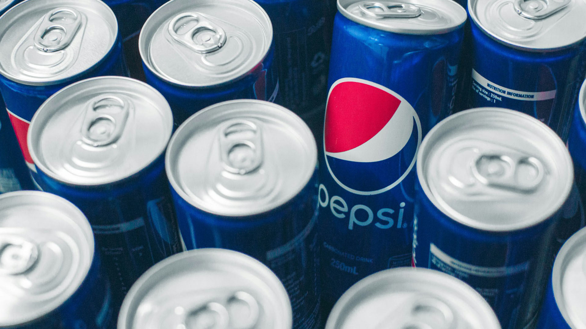 Lattine di Pepsi in primo piano, simbolo del colosso delle bevande che ha annunciato l'acquisizione del marchio prebiotico Poppi. Nuova acquisizione strategica per PepsiCo