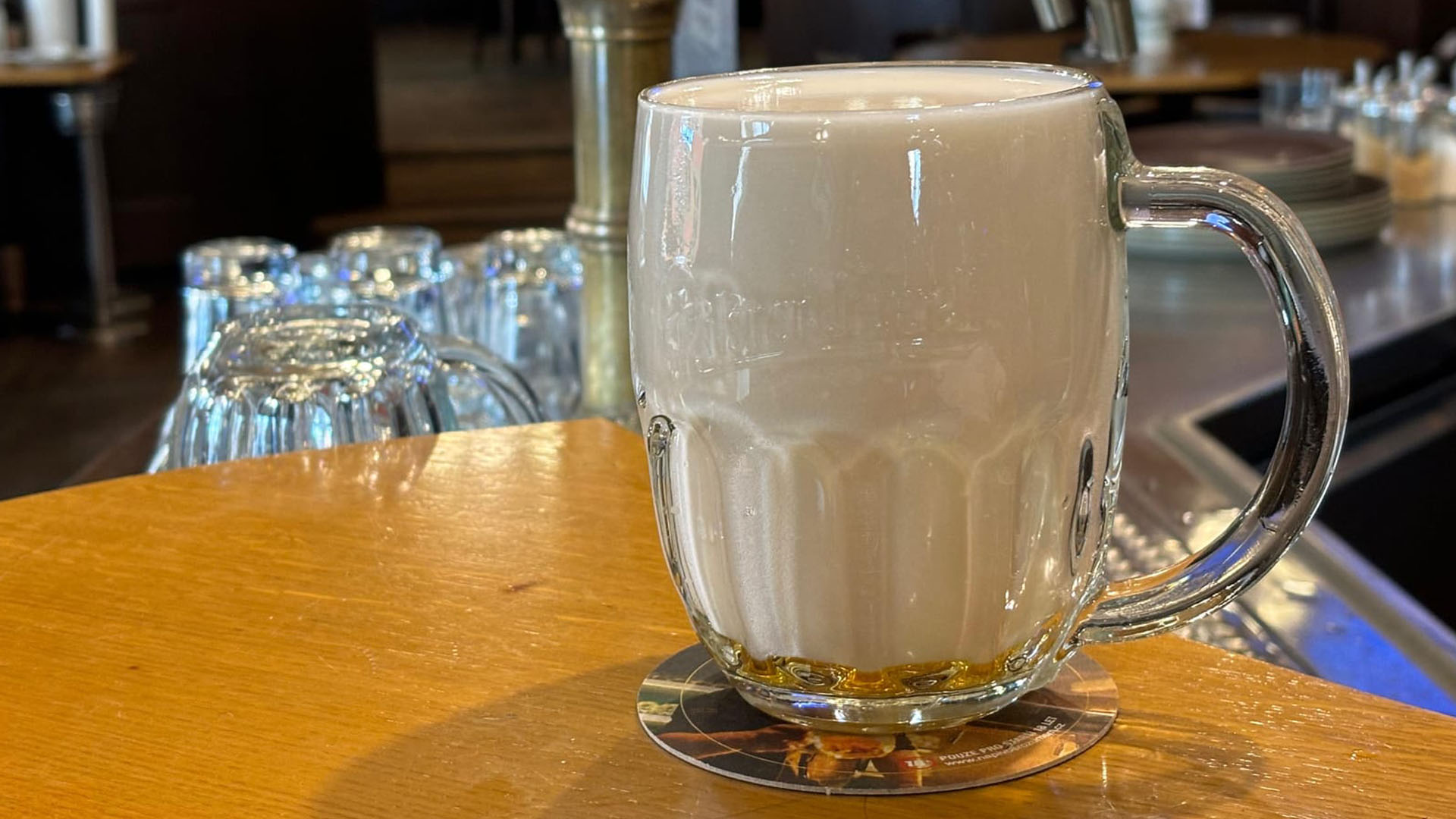 Birra Mlíko in bicchiere tradizionale con schiuma compatta su bancone in stile ceco