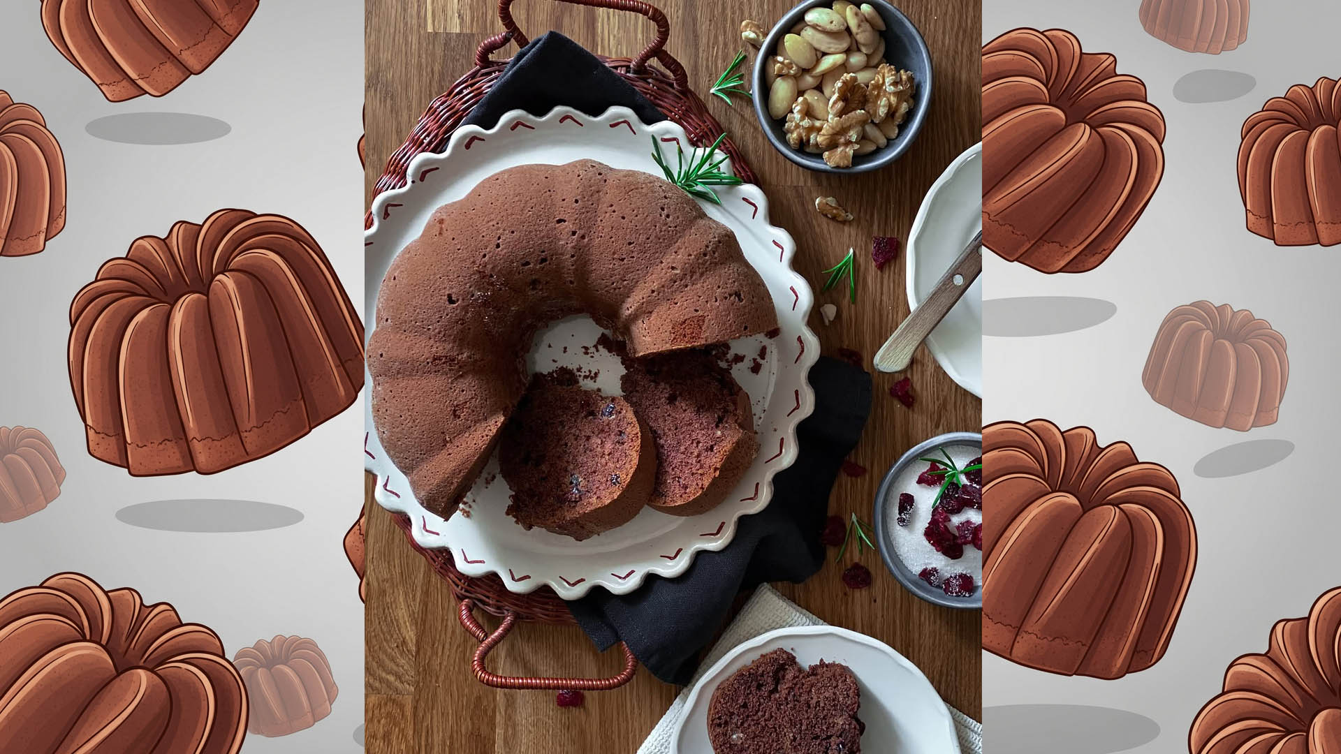 Bundt cake al cacao con frutta secca e mirtilli rossi su piatto da portata, vista dall’alto, affiancata da ciotoline di noci, mandorle e mirtilli disidratati.
