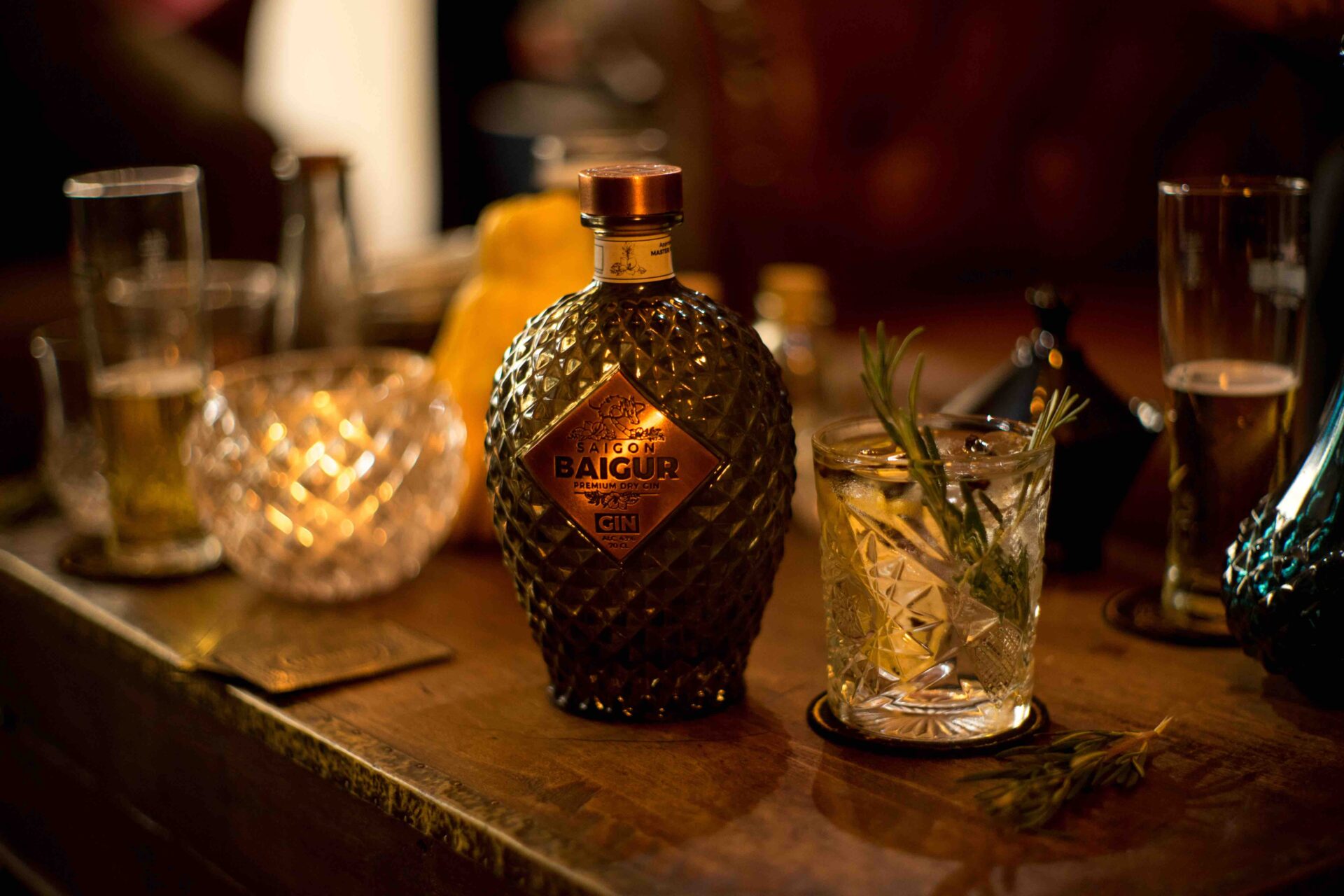 Saigon Baigur Gin premium dry su tavolo con gin tonic e rosmarino in un bar elegante