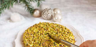 Dolce al pistacchio cremosissimo: la ricetta vellutata delle feste Dolce al pistacchio cremosissimo senza forno ricoperto di granella, con coltello pronto al taglio, dessert al cucchiaio ideale per le feste