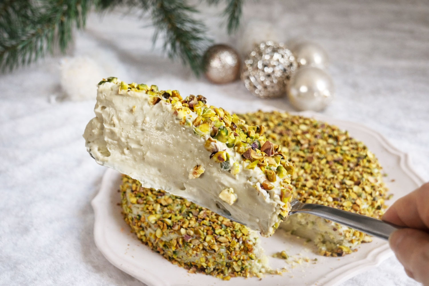 Dolce al pistacchio cremosissimo senza forno servito a fetta, con interno morbido e cremoso e copertura di granella di pistacchio