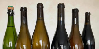 Domaine d’Ici Là: i vini artigianali del Bugey che stanno conquistando gli appassionati Vini artigianali del Bugey del Domaine d’Ici Là esposti in una selezione di sei bottiglie con etichette delle diverse cuvée.