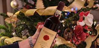 Vini per Natale: rosati e grandi rossi da portare in tavola Vini per Natale: bottiglia di Chianti Classico Riserva 2020 Carpineto davanti all’albero, ideale per abbinamenti delle feste