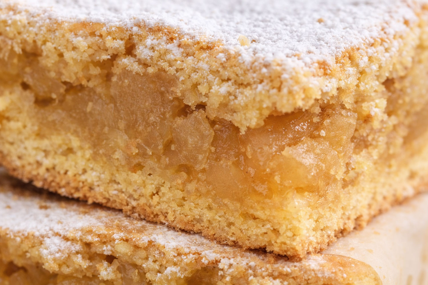 Quadrotti di mele con interno soffice e ripieno alla cannella, evidenziato in primo piano per mostrare consistenza e texture della frolla.