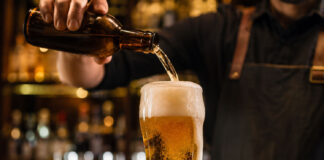 Cosa succede quando si serve male una birra Birra servita male con schiuma eccessiva durante la mescita al bancone di un pub