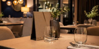 Come rinnovare i tavoli di un ristorante o bar senza sostituirli Cover per tavolo su misura in ecopelle con bordo cucito e mise en place elegante all’interno di un moderno ristorante, bar o hotel.