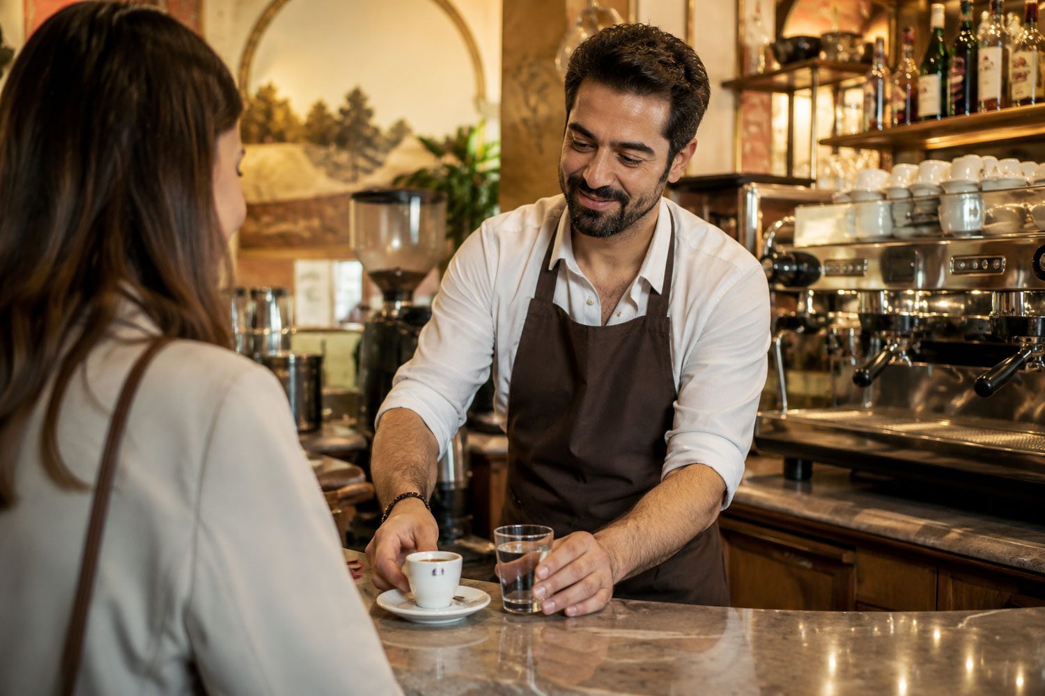 Barista serve un caffè espresso al bancone di un bar italiano